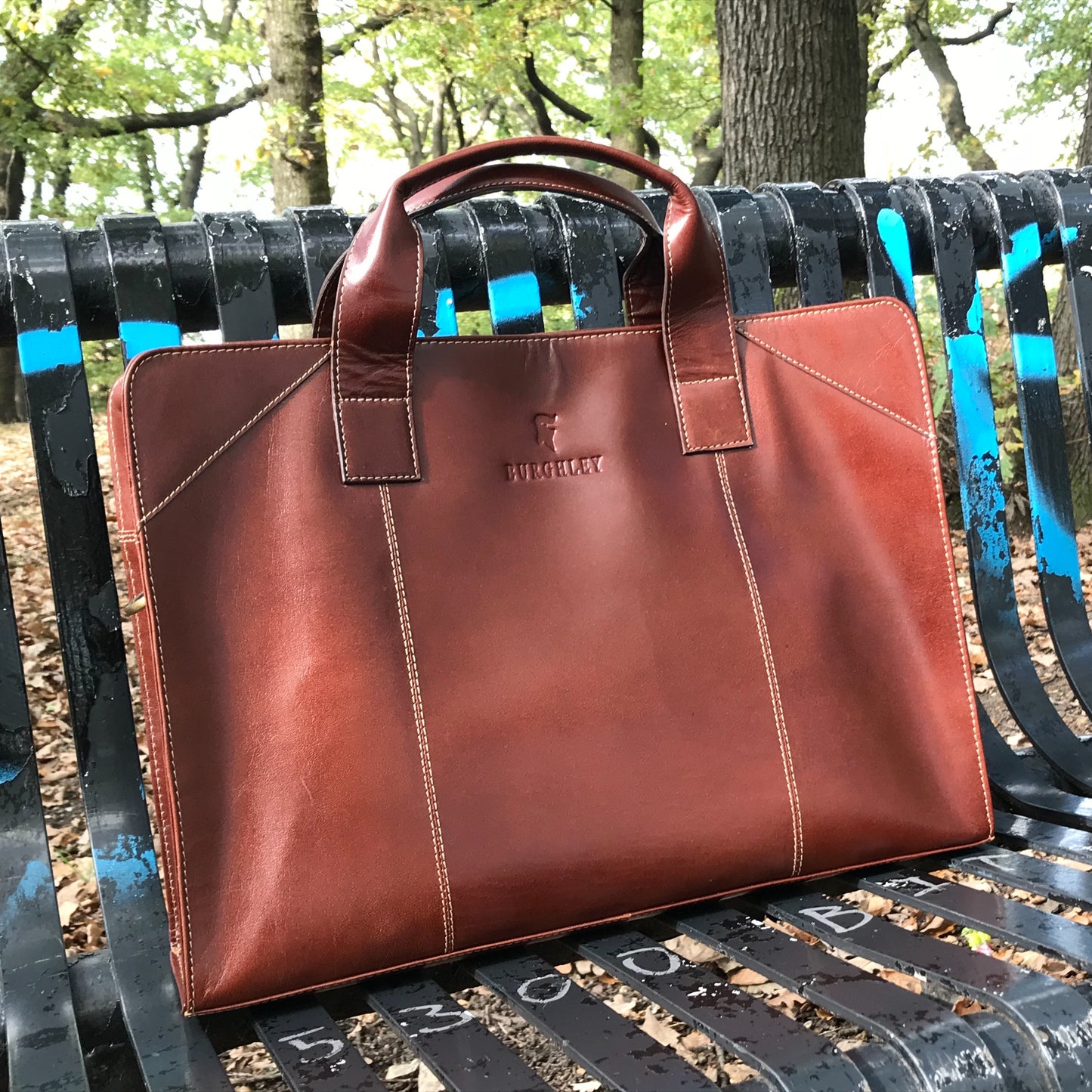 The Easton Briefcase. An elegant and modern work bag by Burghley Bags. Handmade from luxurious chestnut leather, it's large enough for 15" laptops and has a document sleeve. Comes with a detachable shoulder strap.