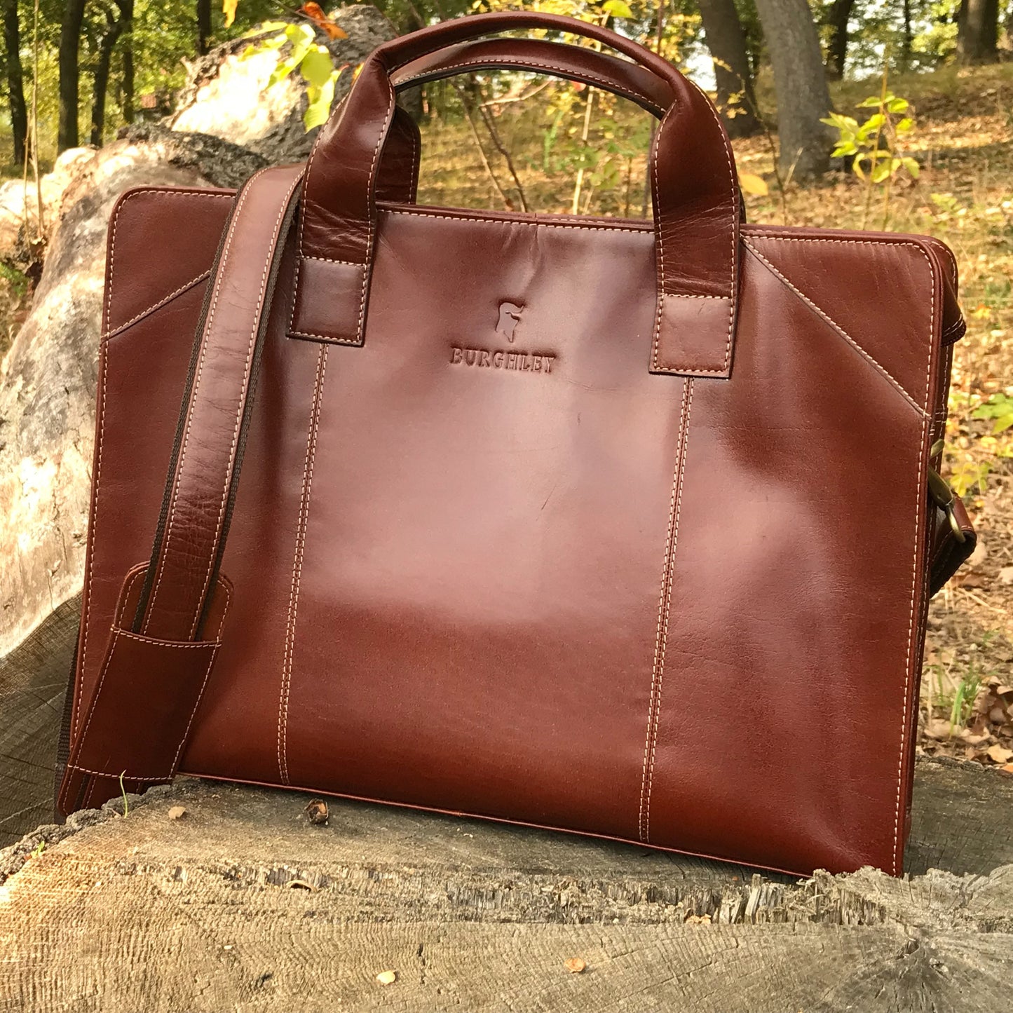 The Easton Briefcase. An elegant and modern work bag by Burghley Bags. Handmade from luxurious chestnut leather, it's large enough for 15" laptops. Comes with a detachable shoulder strap.