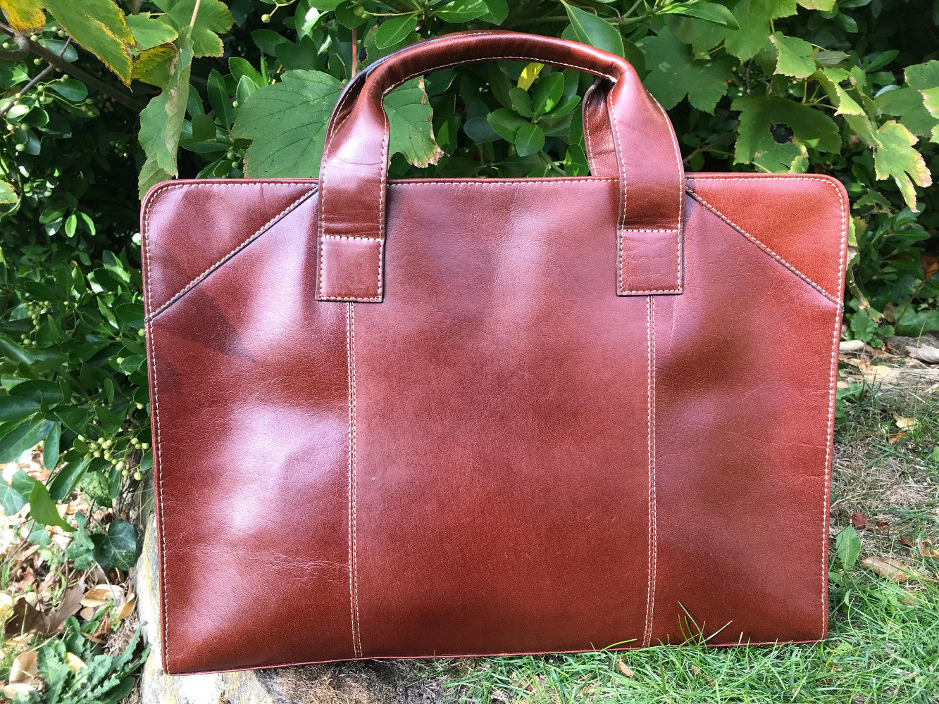 The Easton Briefcase. An elegant and modern work bag by Burghley Bags. Handmade from luxurious chestnut leather, it's large enough for 15" laptops. Comes with a detachable shoulder strap.