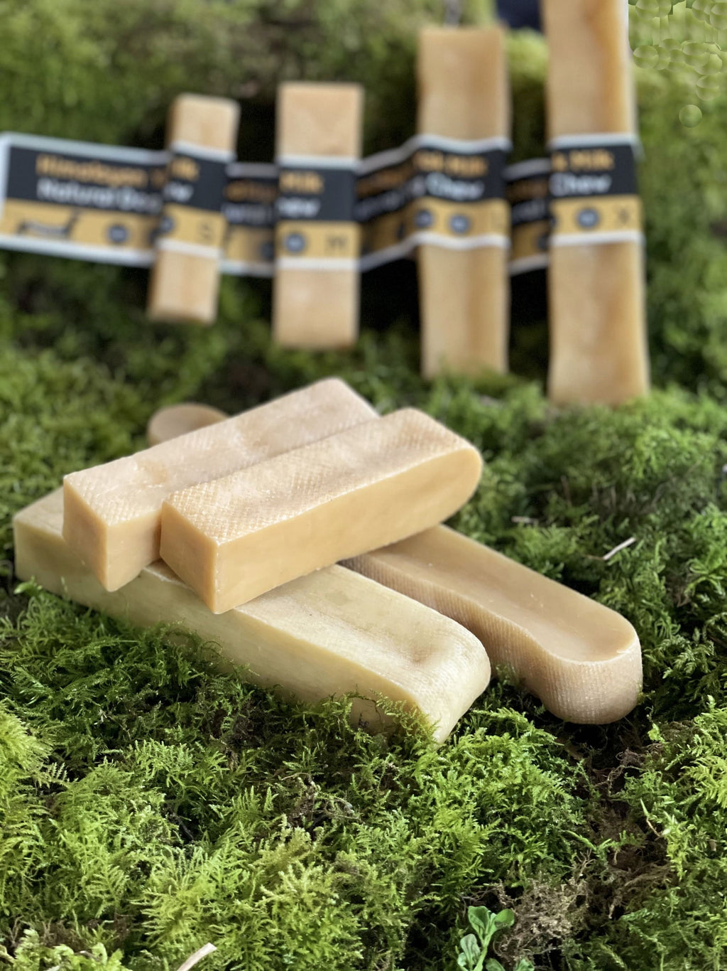 Bar of soap on a green mossy surface with more bars and packaging in the background.
