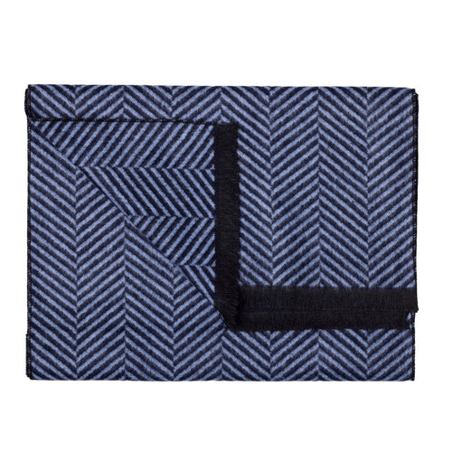 Folded blue and white patterned blanket with a black border on a white background