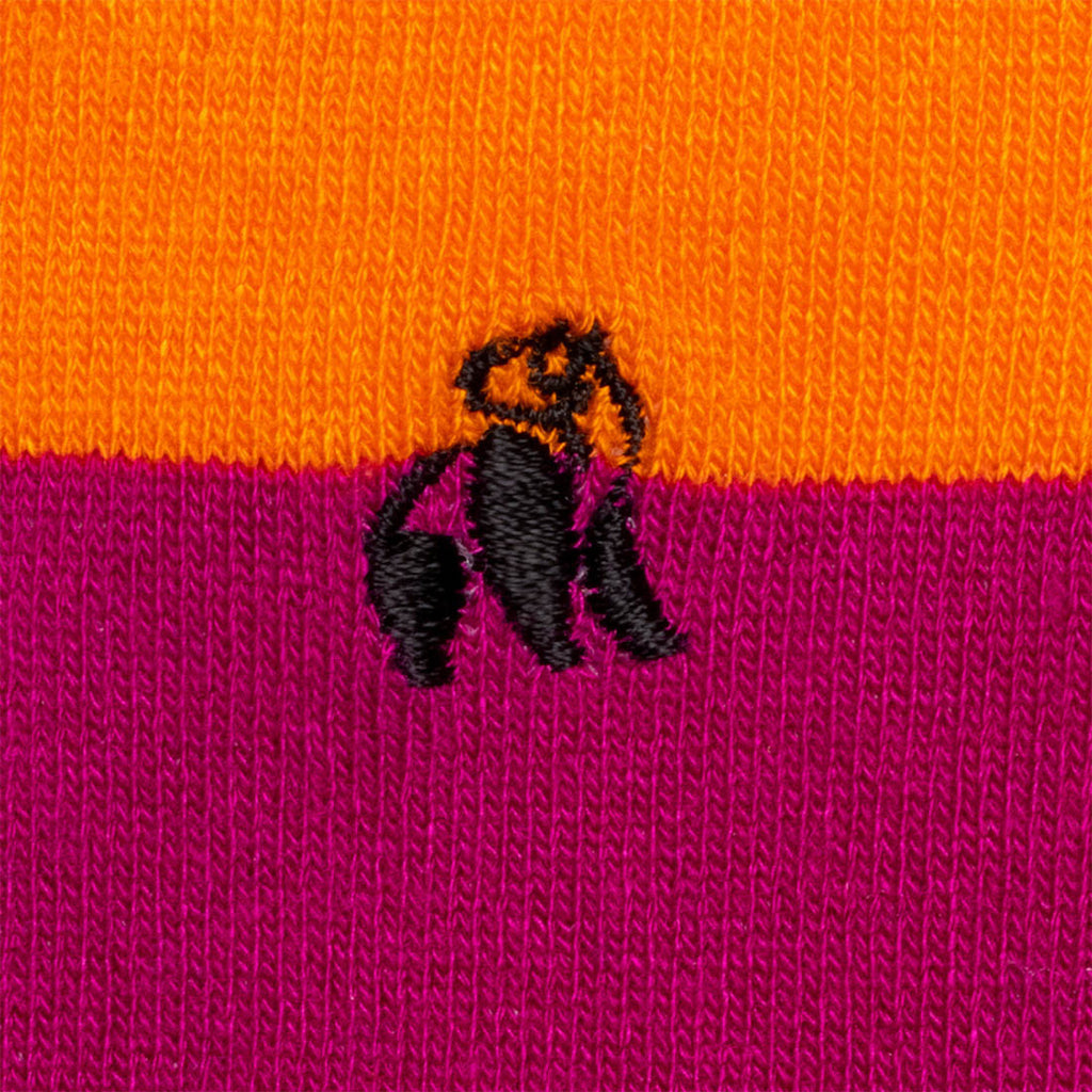 Close-up of a black embroidered design on an orange and pink fabric background