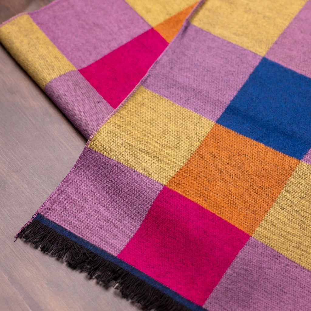 Colorful checkered blanket with fringed edge on a wooden floor