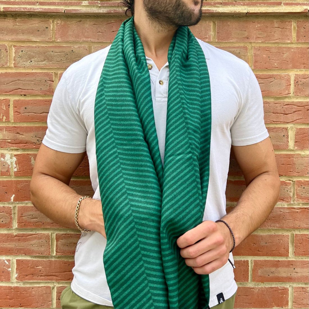 Man wearing a green striped scarf against a brick wall