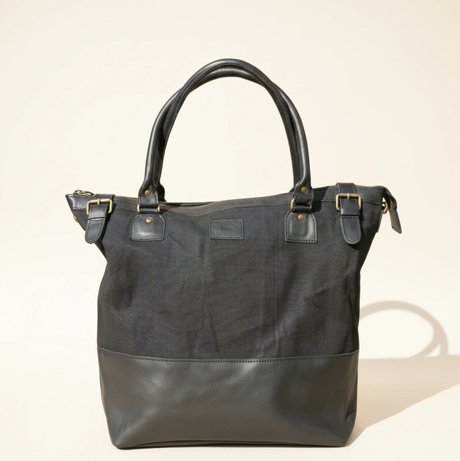 Black handbag with leather accents on a beige background
