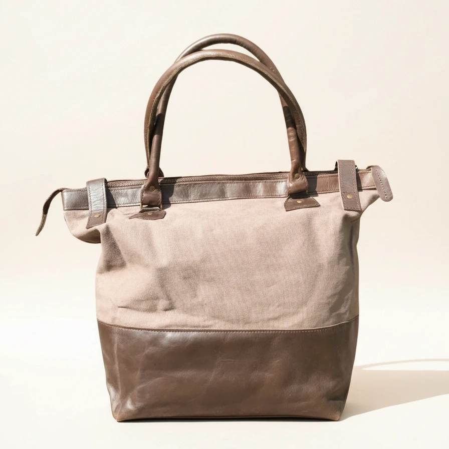 Two-toned handbag with beige top half and brown bottom half on a light background
