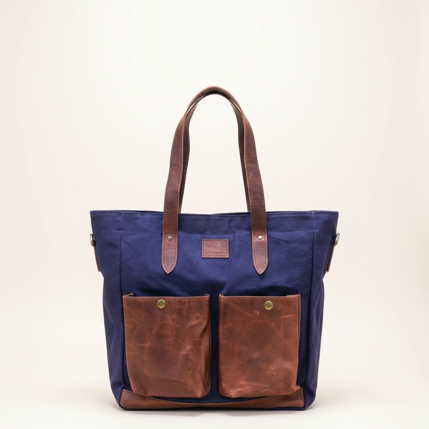 Navy tote bag with brown leather accents on a beige background