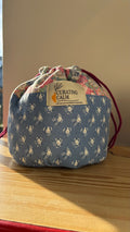 Floral drawstring bag with 'Curating Calm' label on a wooden surface