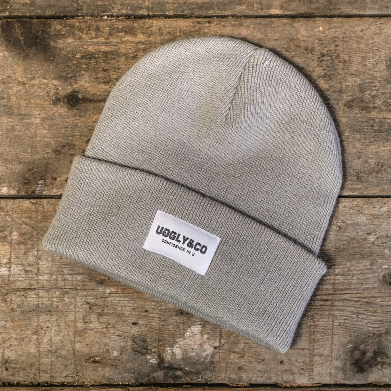 Gray beanie with a label on a wooden surface