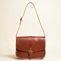 Brown leather bag with a strap on a beige background