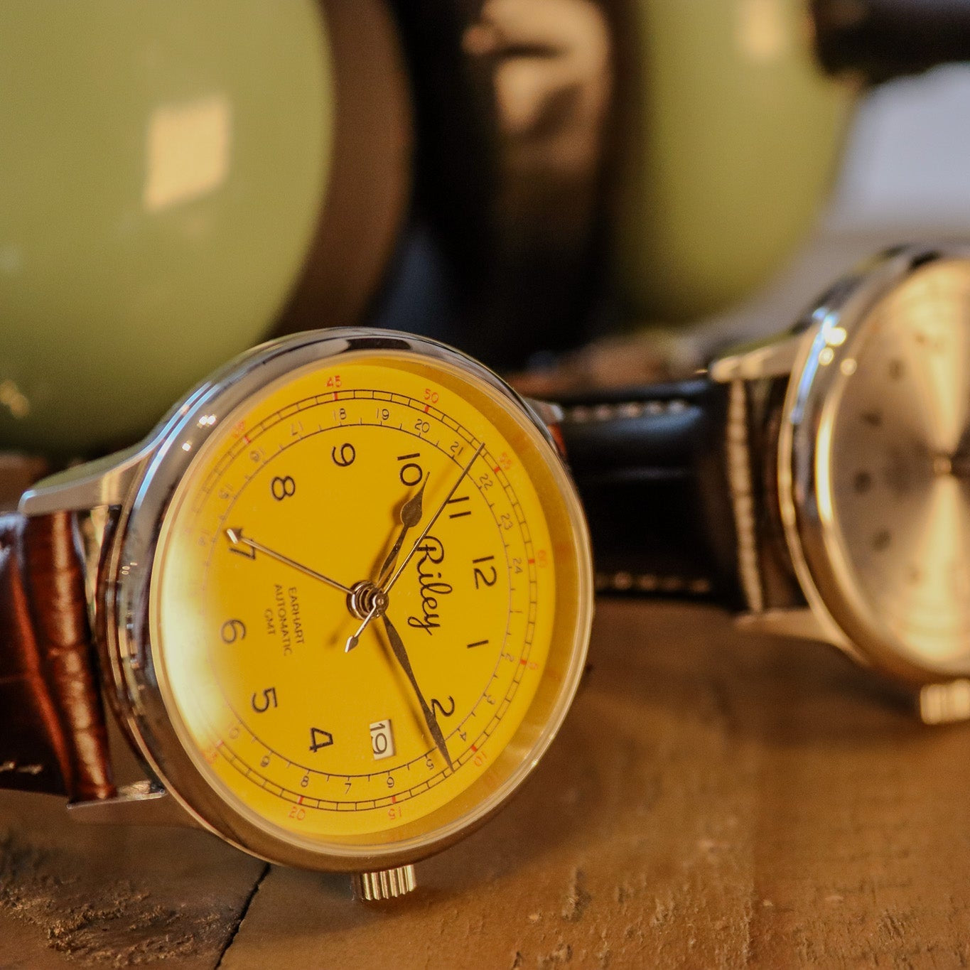 Vintage watch with yellow face and brown leather strap on a wooden surface