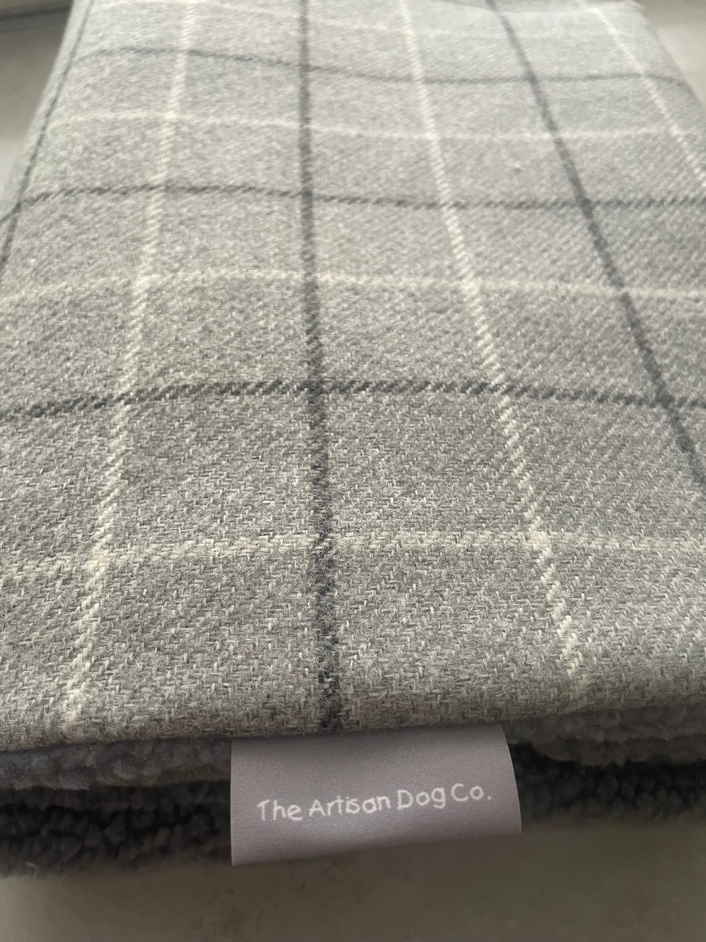 Gray checkered fabric with a label reading 'The Artisan Dog Co.'
