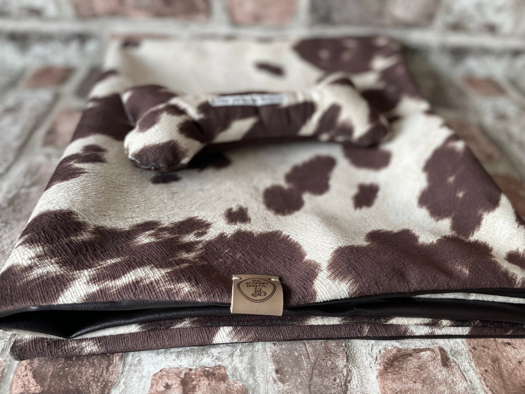 Cow print blanket with a brand logo on a brick surface