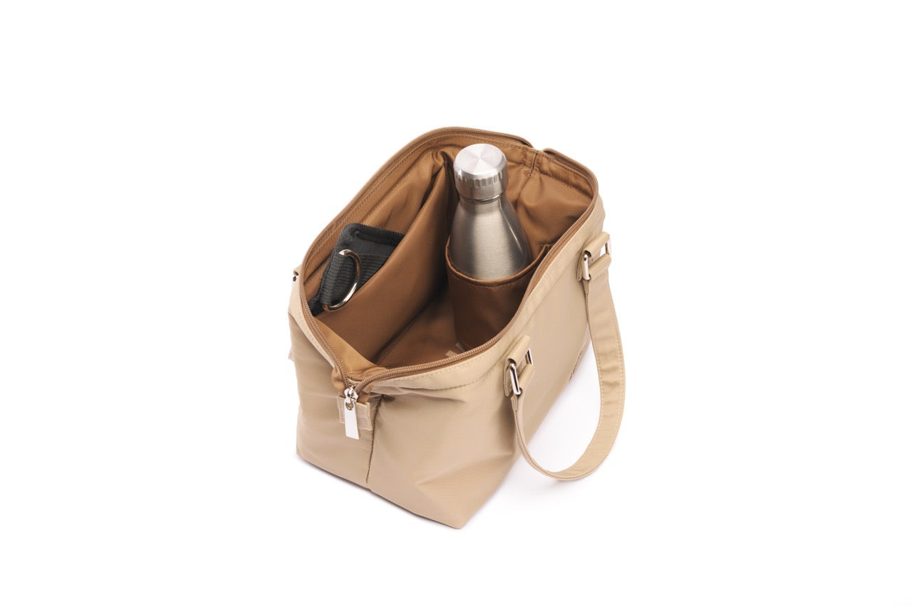 Beige handbag with a bottle and phone inside on a white background