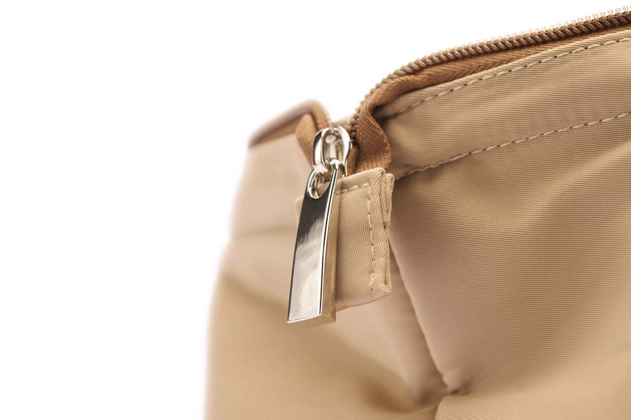 Close-up of a beige bag with a gold zipper on a white background