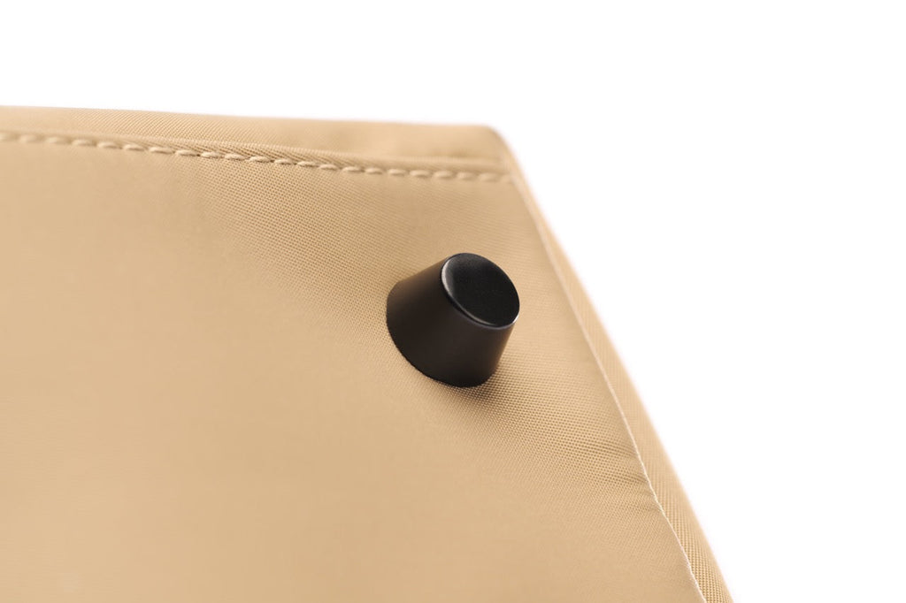 Close-up of a beige fabric surface with a black cylindrical object on a white background