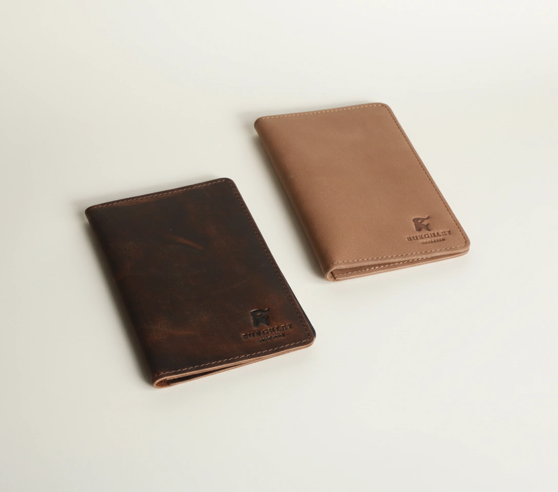 Two brown leather wallets on a light beige background