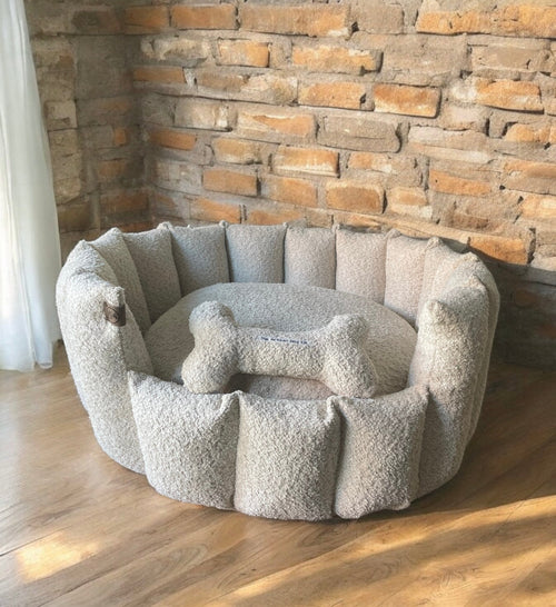 Pet bed with a bone-shaped pillow against a stone wall.
