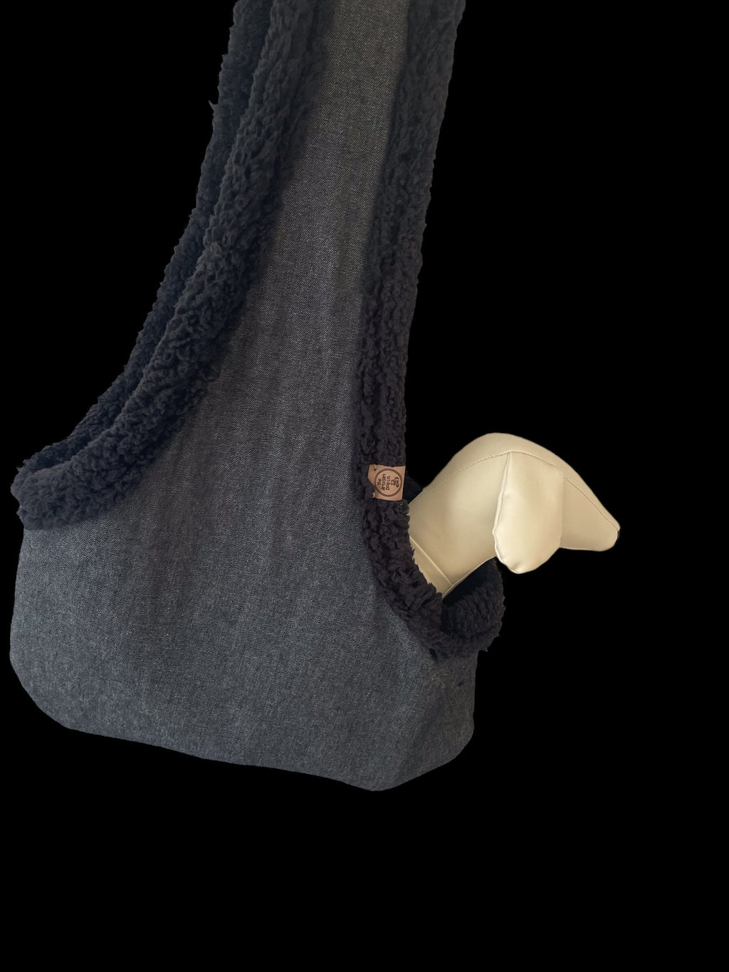 Gray textured bag with a white paw-shaped object on a black background