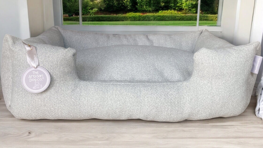 Gray pet bed with a brand tag on a wooden floor, outdoor background