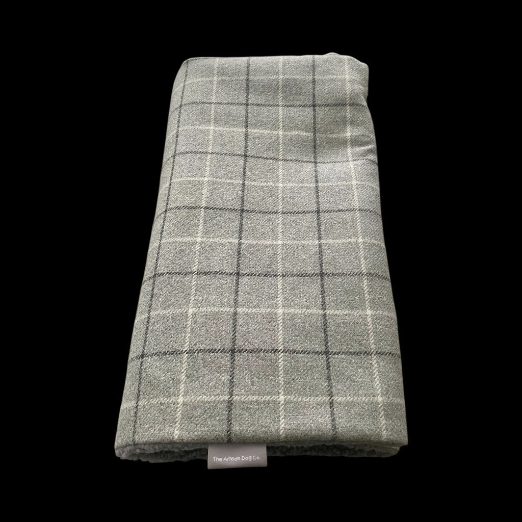 Folded green plaid blanket with a brand label on a black background