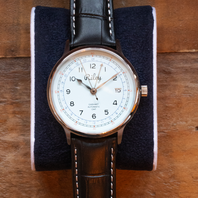 Watch with a brown leather strap on a wooden surface