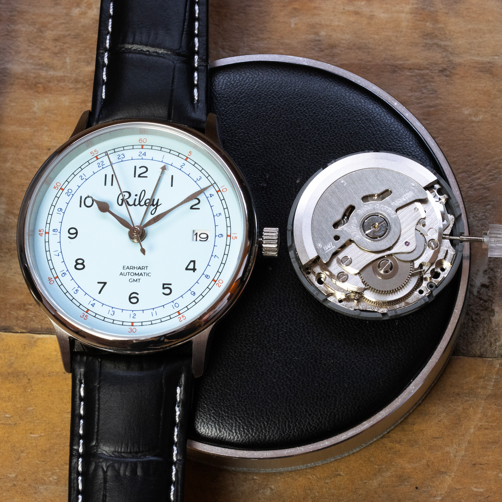 Watch with black leather strap and visible mechanism on a wooden surface