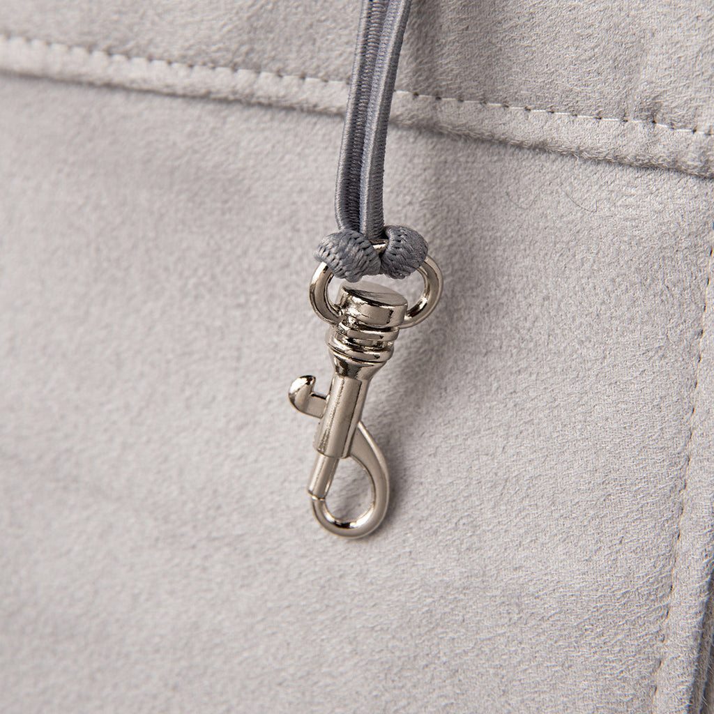 Close-up of a silver clasp on a light gray leather bag.