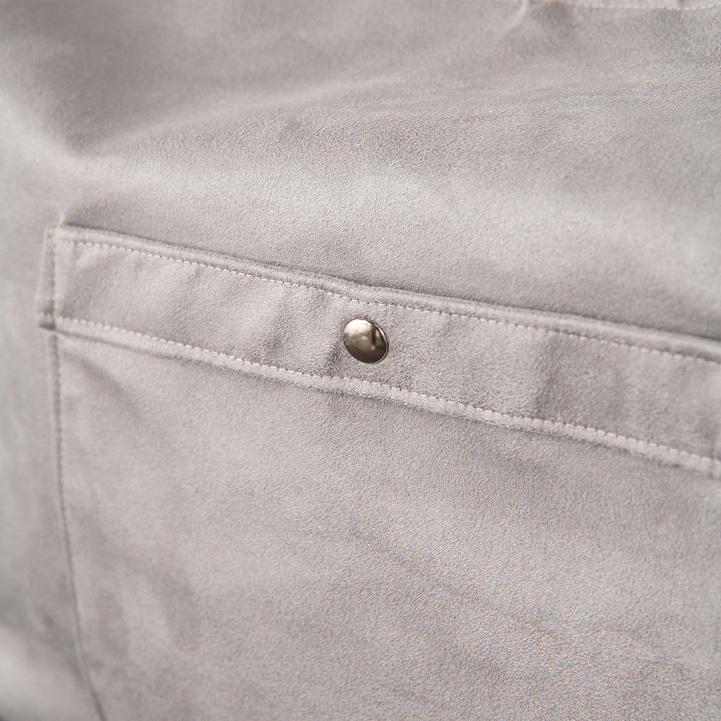 Close-up of a gray fabric pocket with a button on a light gray background