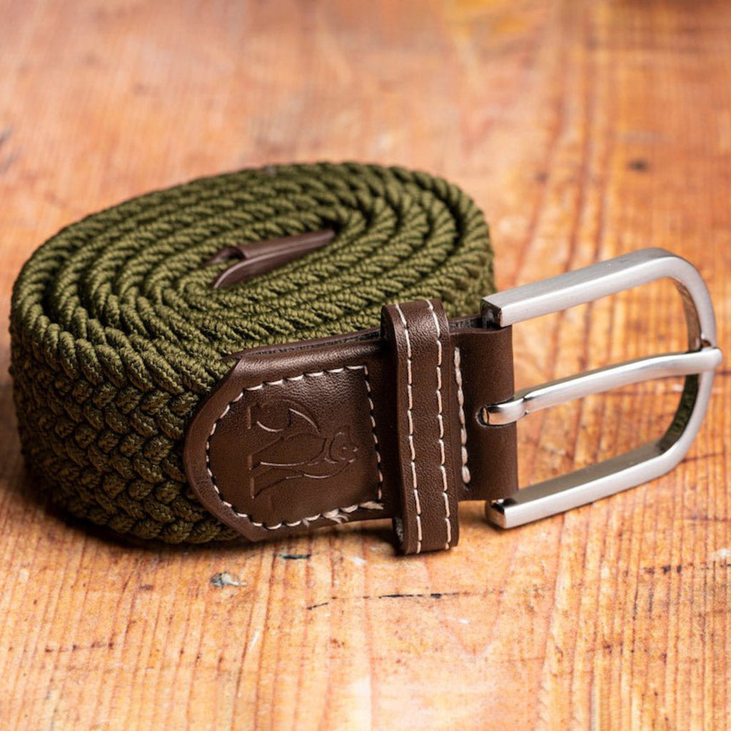 Green braided belt with brown leather buckle on a wooden surface