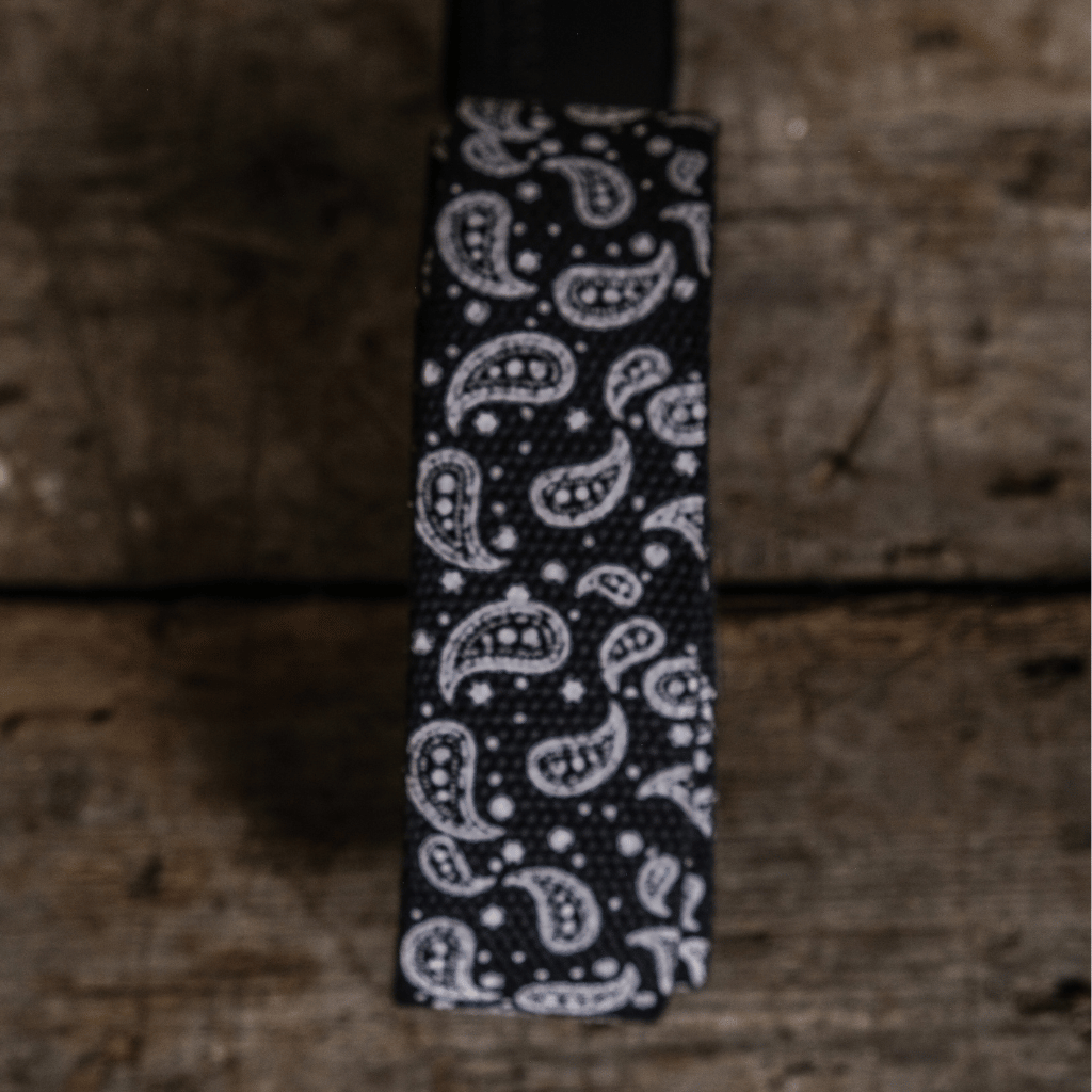 Black tie with white paisley pattern on a wooden surface