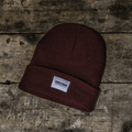 Brown beanie with a label on a wooden surface