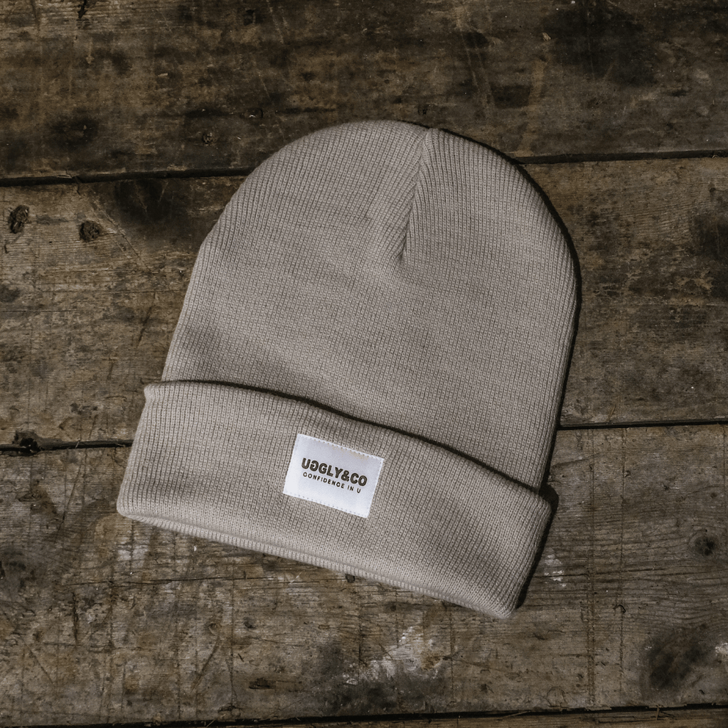 Beige knit beanie with a label on a wooden surface