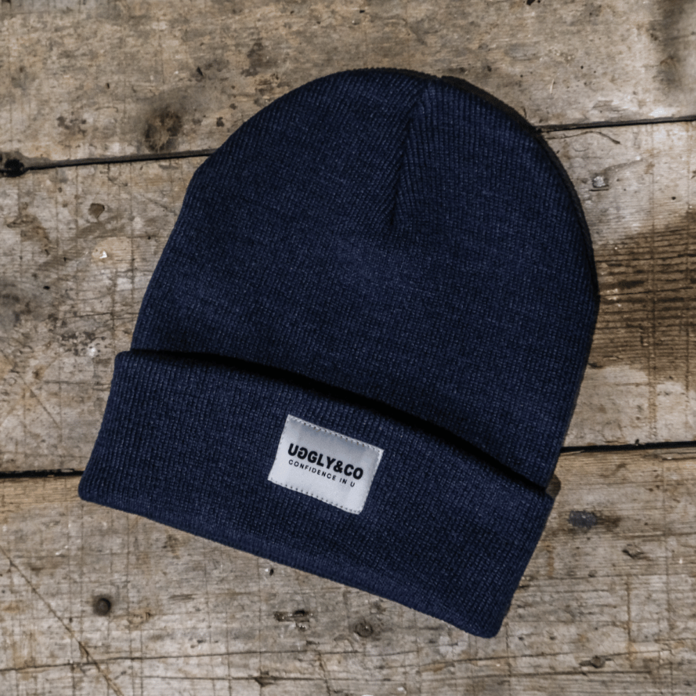 Navy blue beanie with a logo patch on a wooden surface