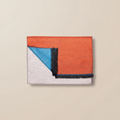 Folded fabric with orange, blue, and gray sections on a beige background