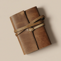 Brown leather-bound book with a strap on a beige background
