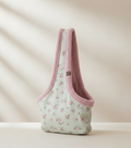 Floral-patterned pet carrier with pink trim on a beige background