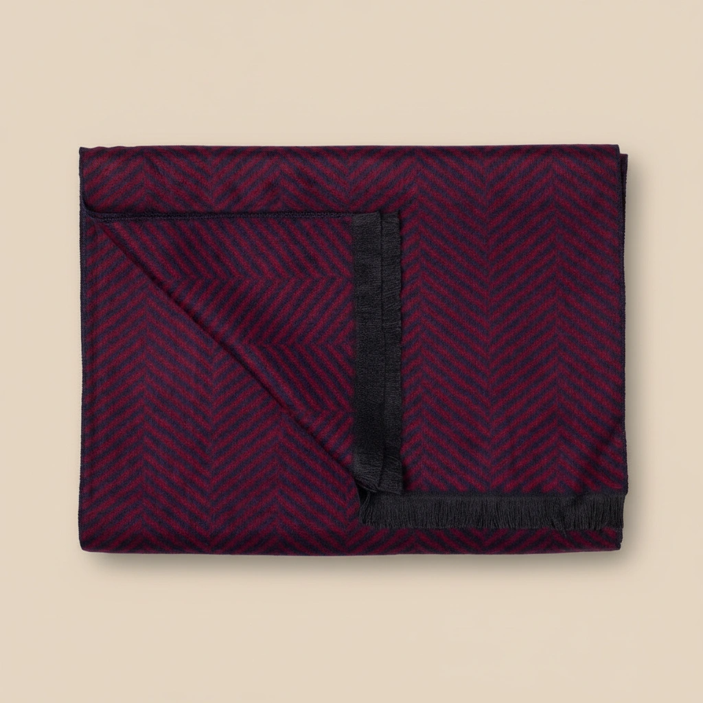 Folded dark red blanket with black edges on a beige background