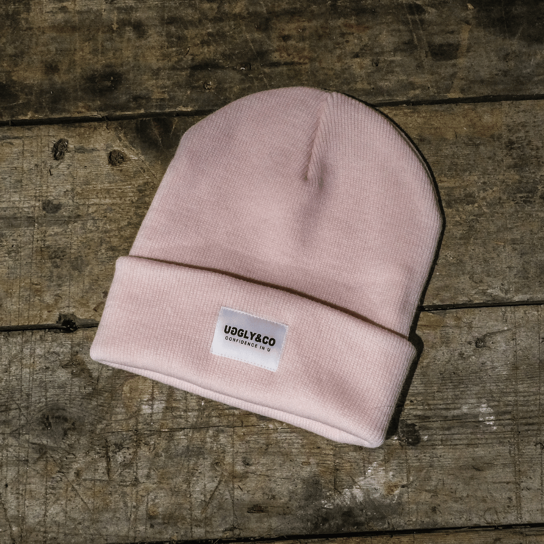 Pink beanie with a label on a wooden surface