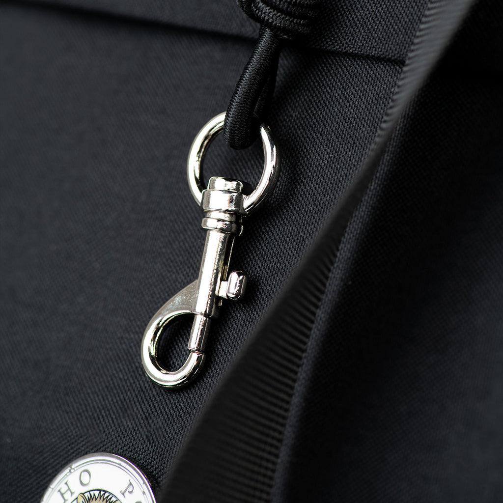 Close-up of a metal clasp on a black bag with a visible brand logo.