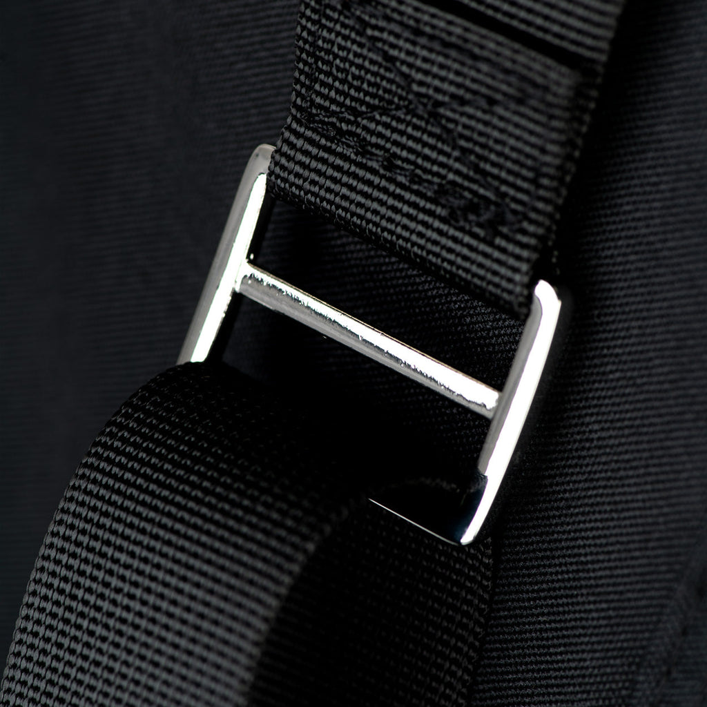Close-up of a black strap with a silver buckle on a dark background