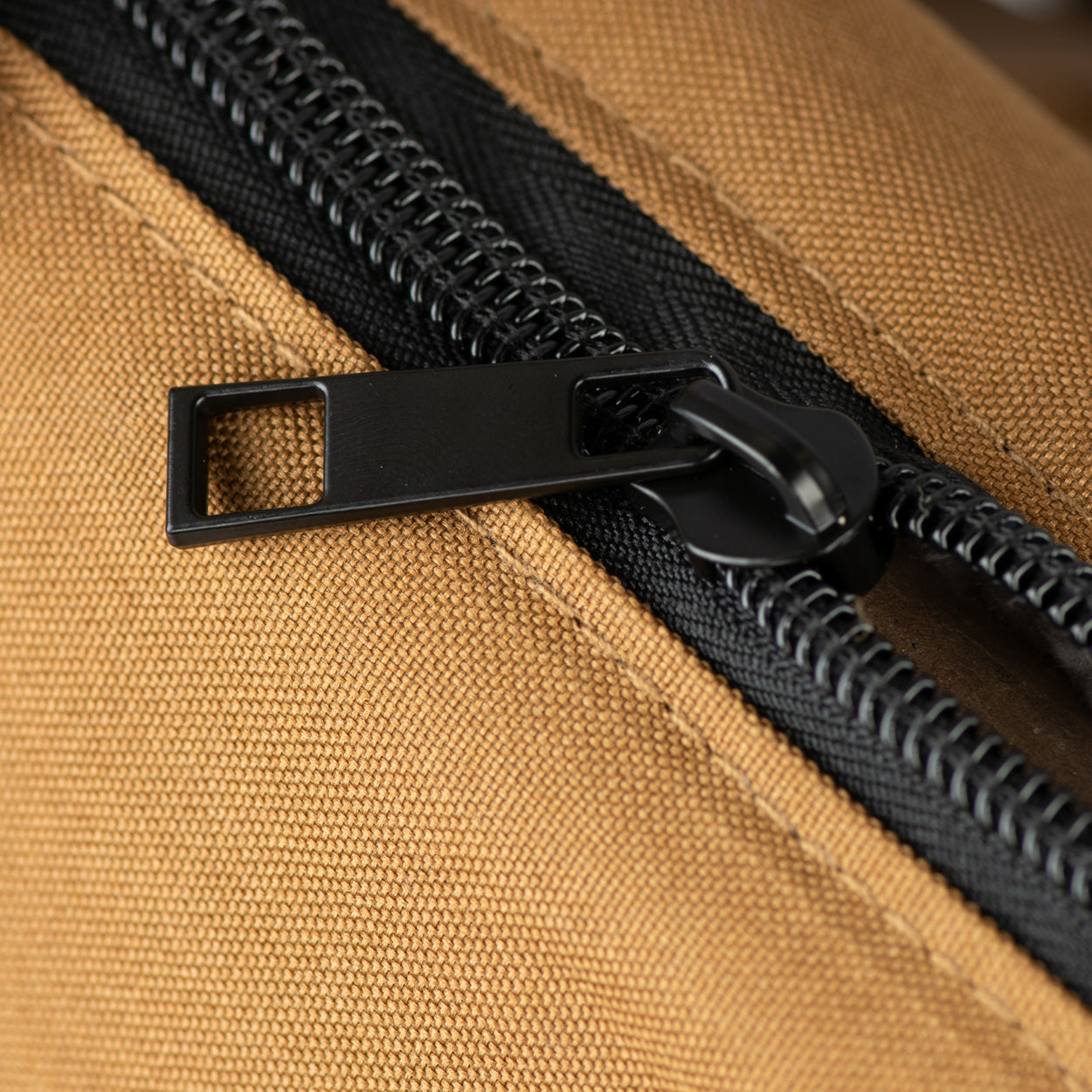 Close-up of a black zipper on a brown fabric surface