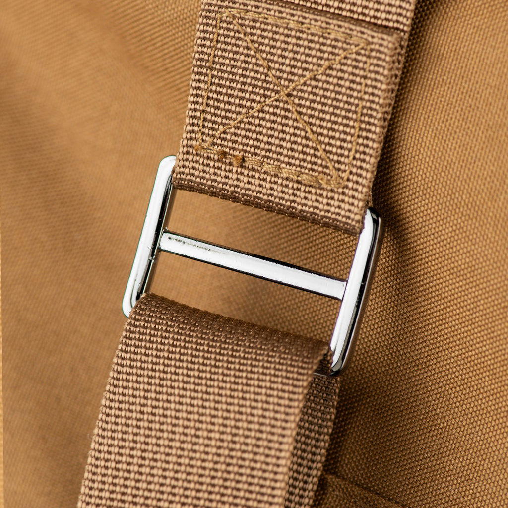 Close-up of a brown strap with a silver buckle on a brown background
