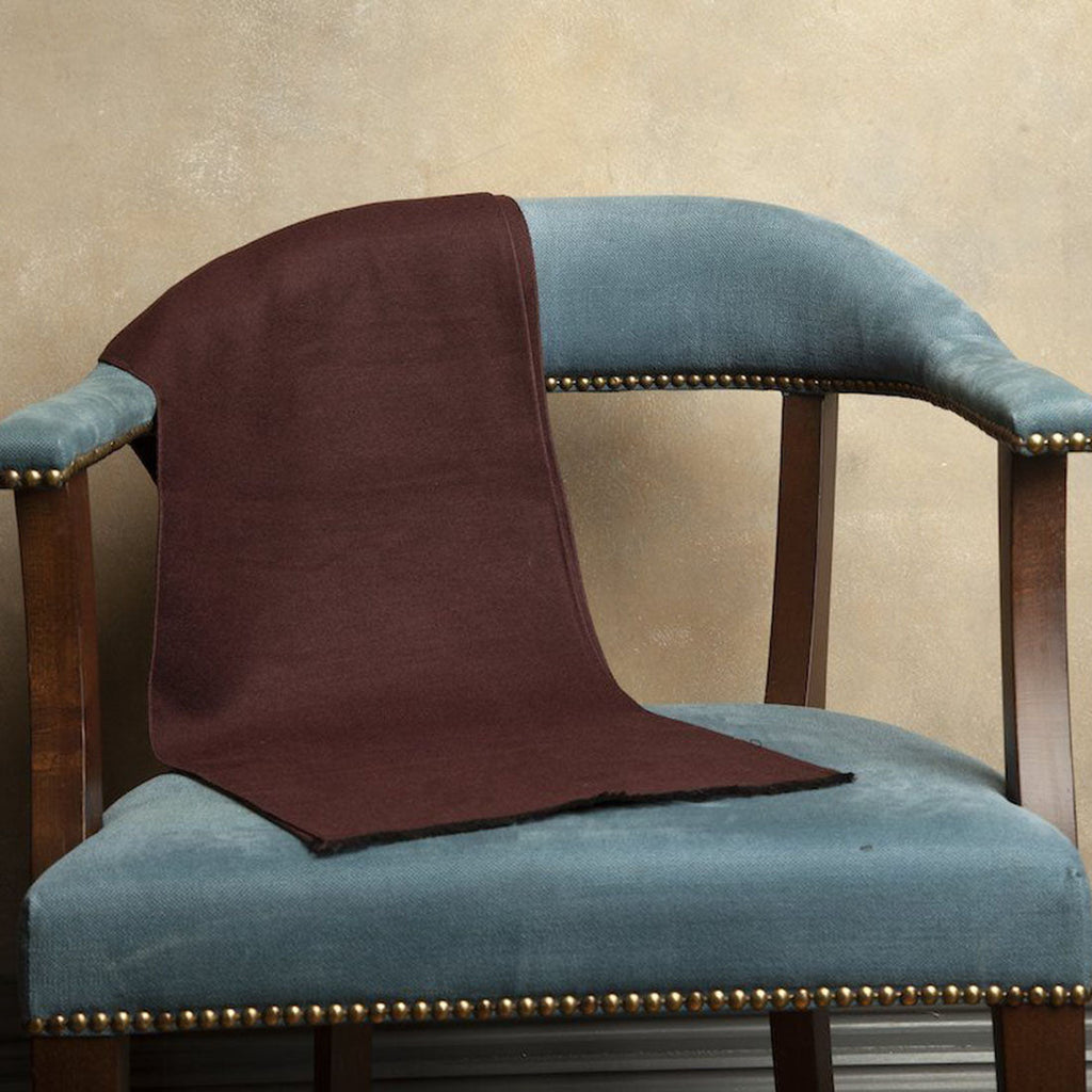 Blue chair with a brown blanket draped over it against a beige wall.