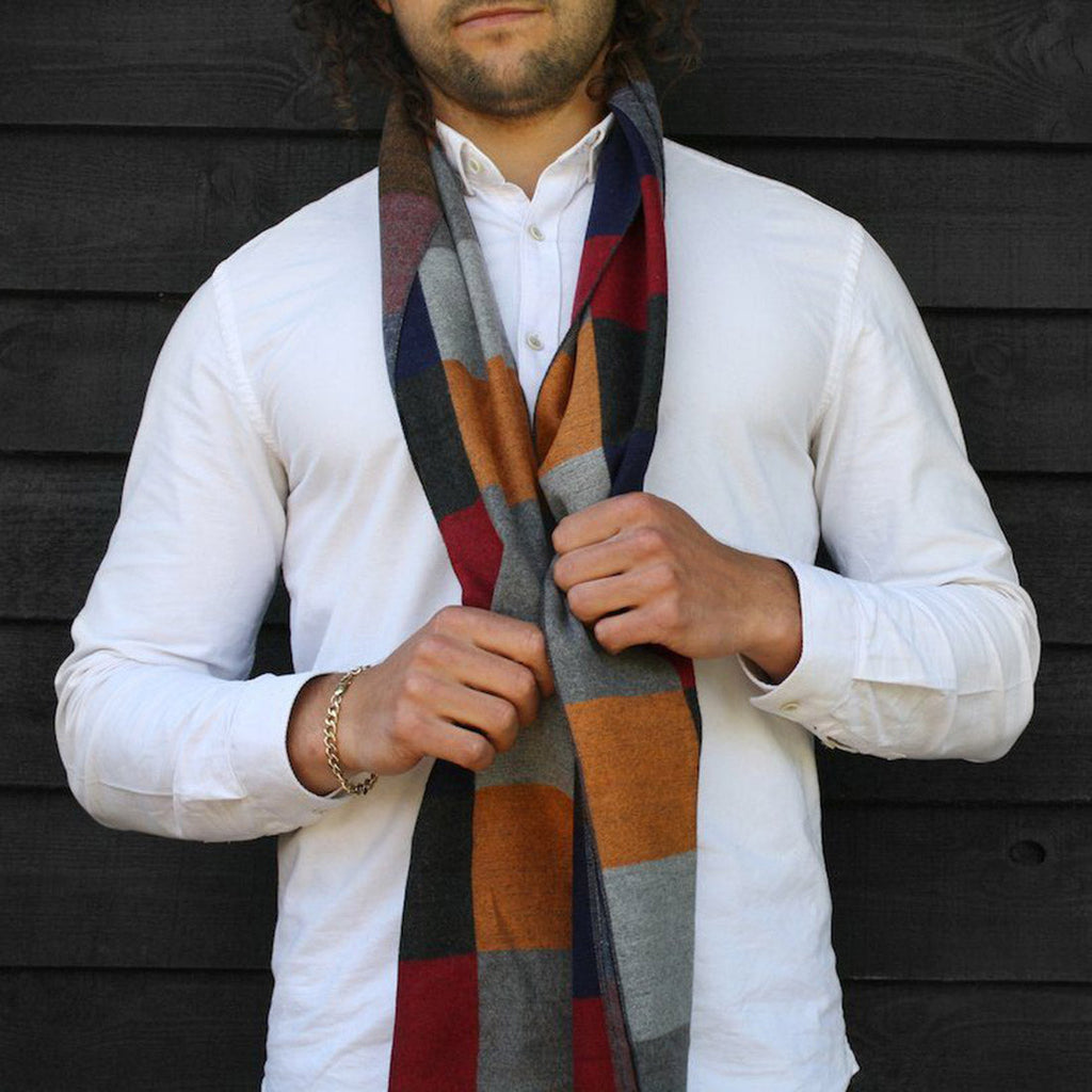 Man wearing a colorful scarf with a white shirt against a dark wooden background