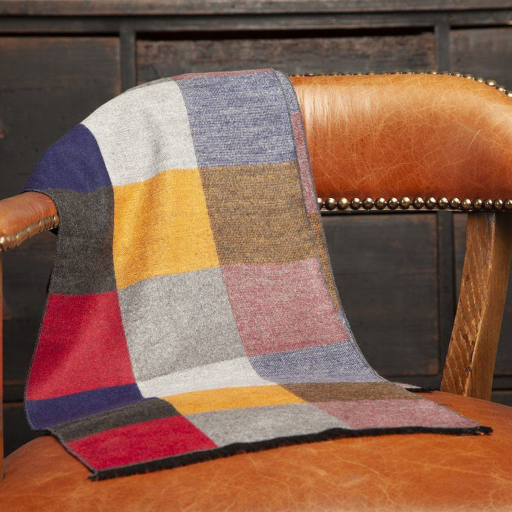 Colorful checkered blanket draped over a brown leather chair.