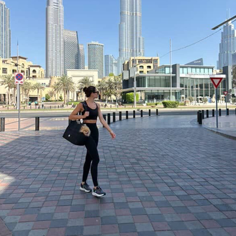 Woman walking on a sidewalk with modern skyscrapers in the background