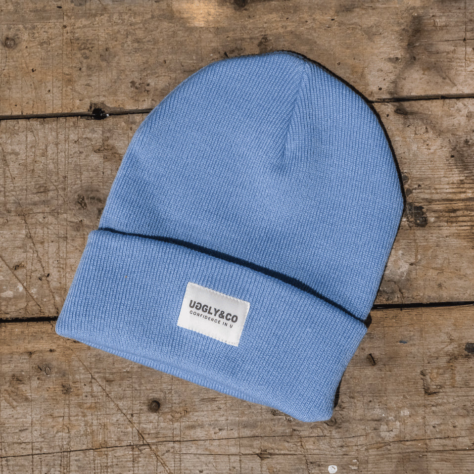 Blue beanie with a visible brand label on a wooden surface
