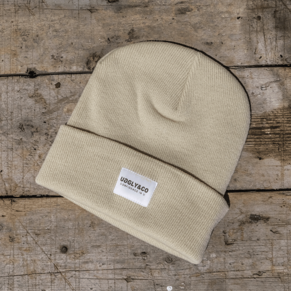 Beige beanie with a label on a wooden surface