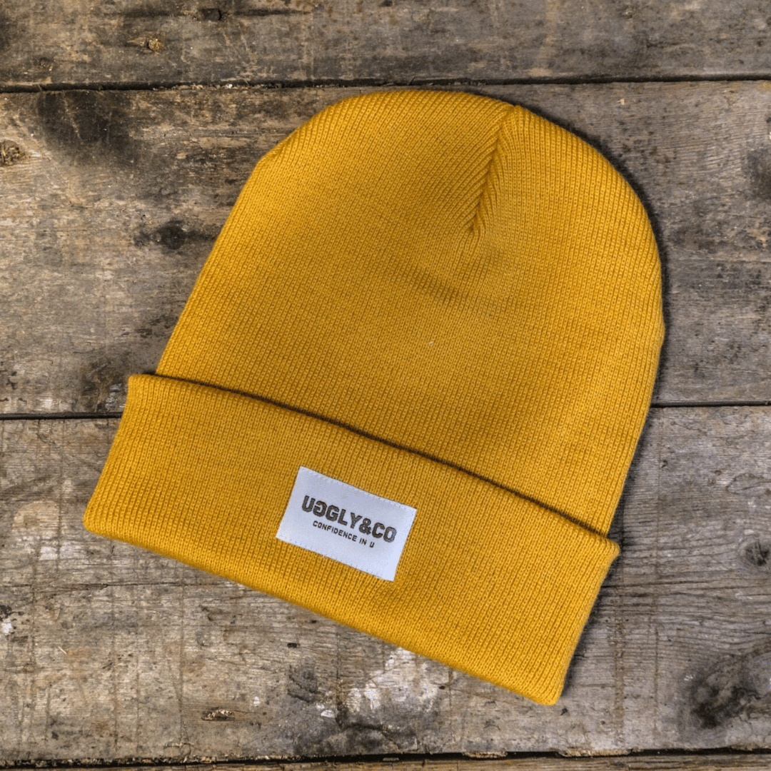 Yellow beanie with a label on a wooden surface